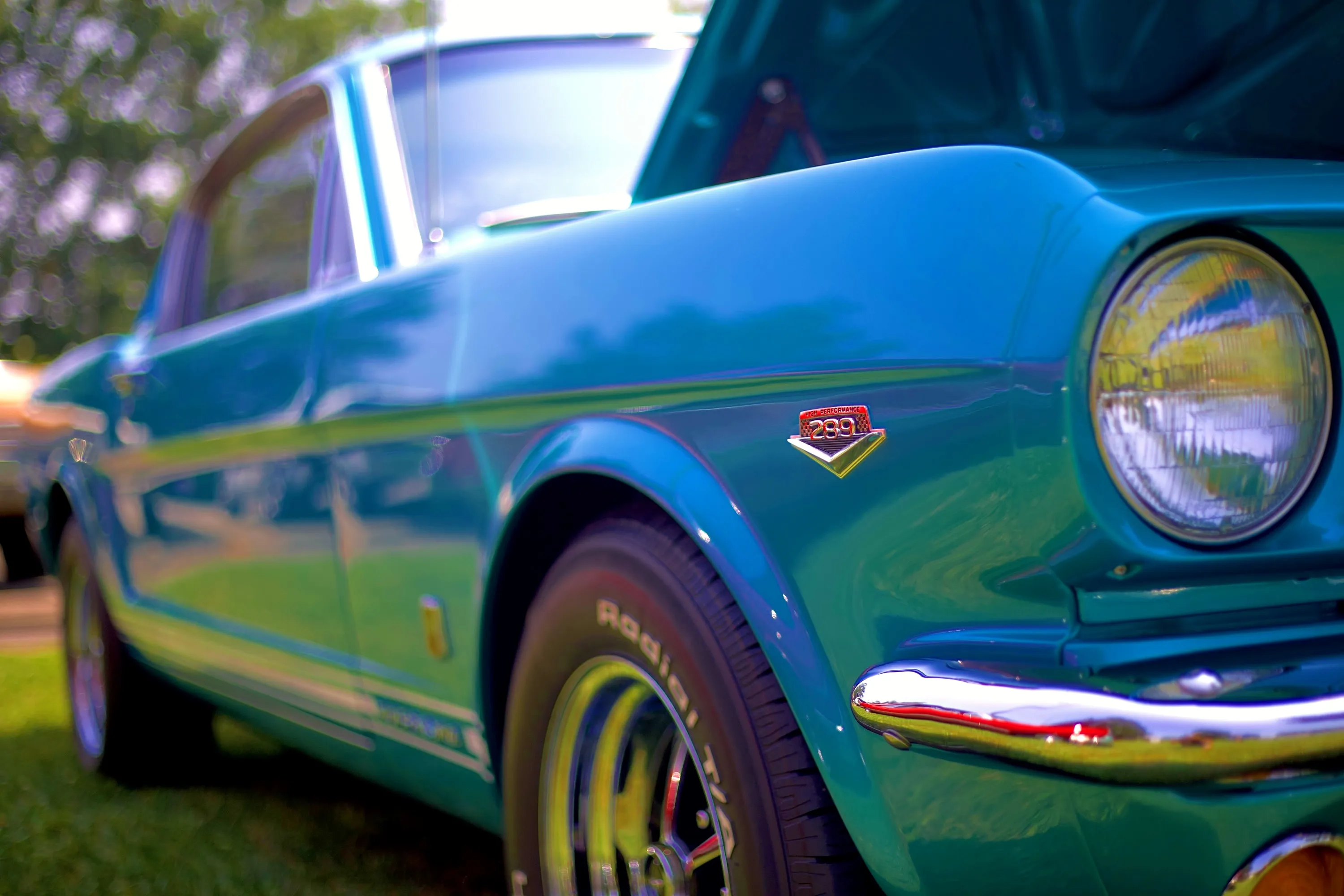 Vehicle detail — shallow depth of field isolates the paint, chrome and performance badging of a classic automobile.
